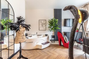 Un saló modern amb una banyera blanca gran, una cadira vermella i una escultura singular.