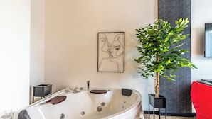 A modern bathroom with a freestanding bathtub, a potted plant, and a framed artwork on the wall. - Luxury Suite - Tentazioni Nascoste (Perugia)