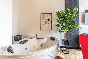 A modern bathroom with a freestanding bathtub, a potted plant, and a framed artwork on the wall. - Luxury Suite - Tentazioni Nascoste (Perugia)