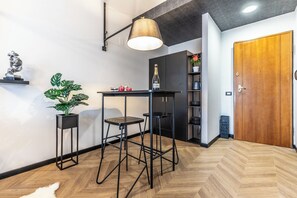 Un interior modern amb un paviment de fusta en disseny de petxina, una barra de metall negre amb tamborets, una làmpada penjant i una porta de fusta.