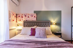 Ein ordentlich bezogenes Bett mit einer gesteppten Kopfteile, eine dekorative Wand mit floralen Anordnungen und Nachttischlampen.