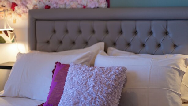 A bed with white and pink pillows, a tufted headboard, and a floral wall decoration. - Luxury Suite - Tentazioni Romantiche (Perugia)