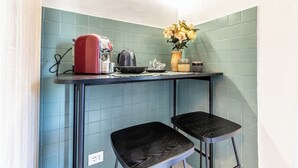 A kitchen with teal tiles, a red kettle, a vase with flowers, and two black stools. - Luxury Suite - Tentazioni Romantiche (Perugia)