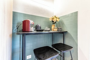 A kitchen with teal tiles, a red kettle, a vase with flowers, and two black stools. - Luxury Suite - Tentazioni Romantiche (Perugia)