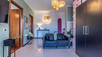 Ein modernes Wohnzimmer mit einem schwarzen Ledersofa, einer Holztür, einem schwarzen Schrank, einem an der Wand montierten Fernseher und einer Wand mit Blumen als Dekoration.