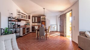 A spacious living area with a dining table and chairs, a sofa, and a kitchen area with cabinets and appliances. - A 15 Miglia da Roma (Riano)