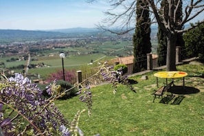 A grassy area with a bench and a table, overlooking a town and hills. - Casetta Stella (Assisi)