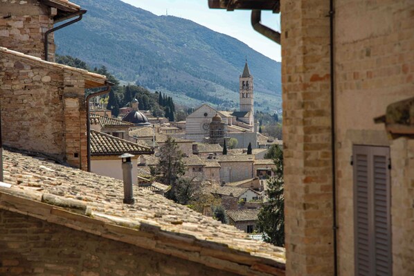 A historic town with stone buildings, a prominent church with a bell tower, and a mountainous backdrop.