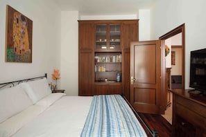A bedroom with a bed, wooden wardrobe, and a television. - Casetta Stella (Assisi)