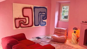 A pink-themed room with a modern sofa, a glass coffee table, and a large abstract painting on the wall.