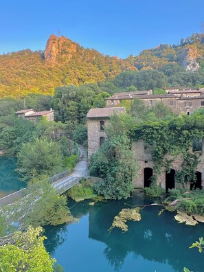 Un ponte in pietra che scavalca un fiume, con vegetazione circostante e montagne sullo sfondo.