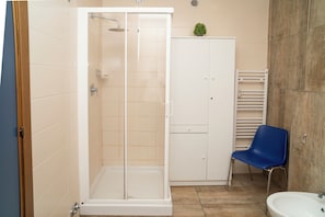 A bathroom with a glass-enclosed shower, a white cabinet, a blue chair, and a sink. - Blues House (Perugia)