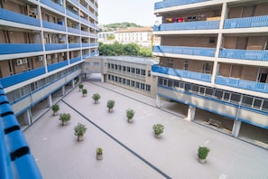 Un edificio de varios pisos con balcones, un patio central con plantas en macetas y un edificio de diseño moderno.