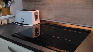 A kitchen with a built-in induction cooktop, a toaster, and a stainless steel range hood. - La Casetta di Piazza Vittorio (Rome)
