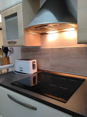 A kitchen with a built-in induction cooktop, a toaster, and a stainless steel range hood. - La Casetta di Piazza Vittorio (Rome)