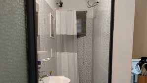 A narrow bathroom with a white sink, toilet, and shower area. - La Casetta di Piazza Vittorio (Rome)