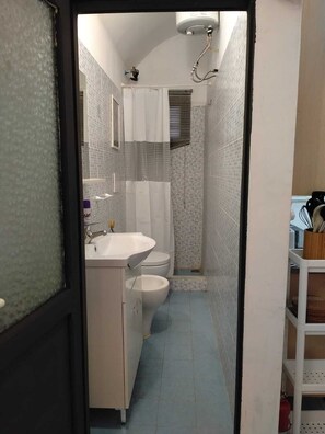 A narrow bathroom with a white sink, toilet, and shower area. - La Casetta di Piazza Vittorio (Rome)
