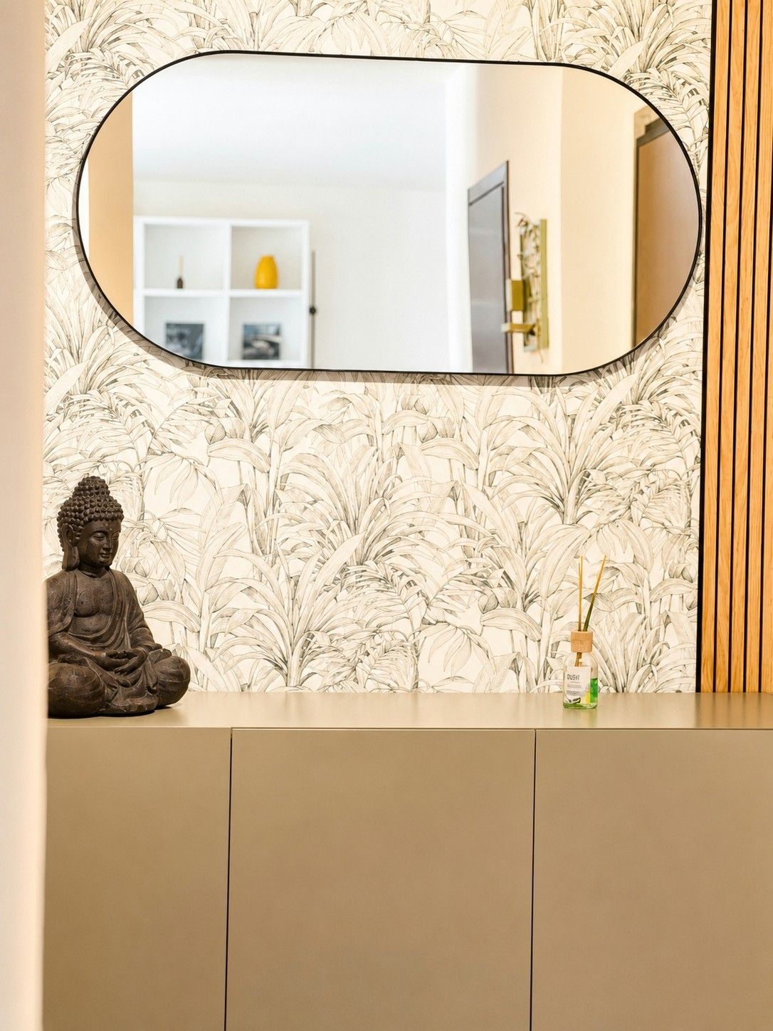 A room with a mirror, a statue, and a shelf with a bottle.