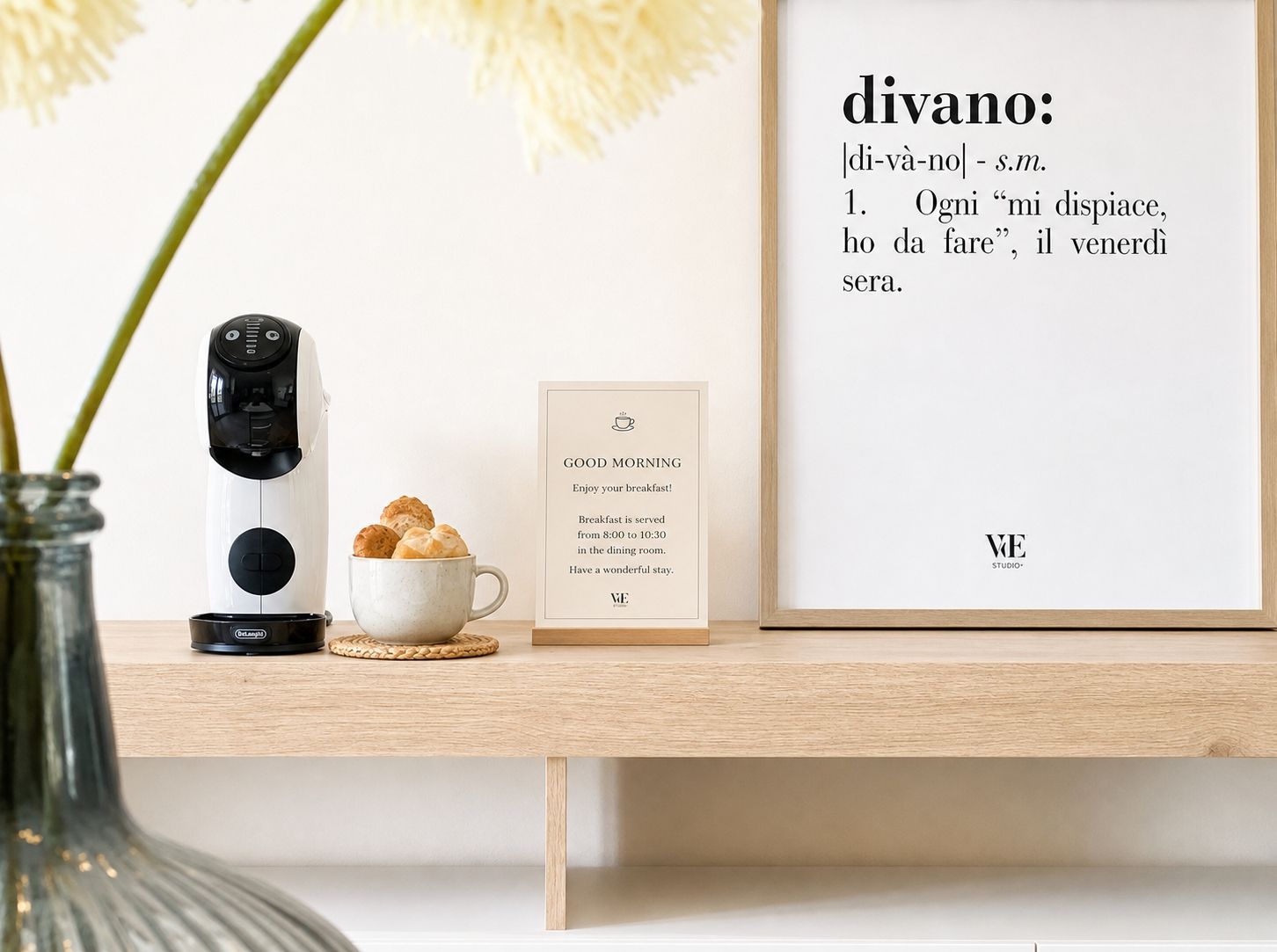 A coffee maker, a cup of coffee, a framed quote, and a sign on a wooden table.