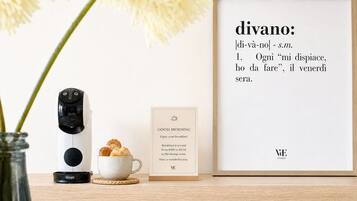 A coffee maker, a cup of coffee, a framed quote, and a sign on a wooden table.