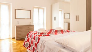 Un dormitorio con cama, cómoda, espejo y armario.