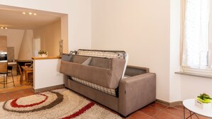 Un espacio habitable compacto con sofá, zona de comedor y ventana con cortinas.