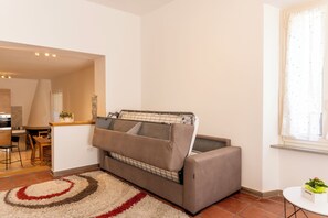 A compact living space with a sofa, a dining area, and a window with curtains.