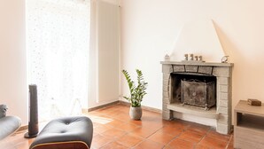 Una sala de estar con chimenea, un radiador, una planta en maceta y un sofá.