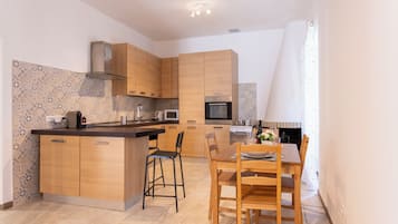 Une cuisine moderne avec des meubles en bois, un îlot central et un coin repas comprenant une table et des chaises.
