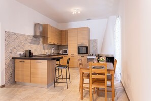 A modern kitchen with wooden cabinets, a central island, and a dining area with a table and chairs.