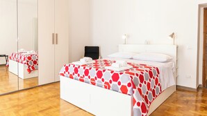 Habitación de hotel con una cama grande, un espejo, un armario y una mesita de noche con lámpara.