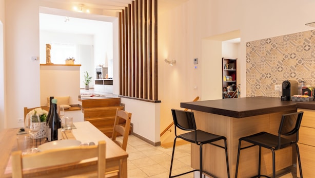 Una cocina moderna con una isla de madera, taburetes de bar y un comedor con mesa y sillas.