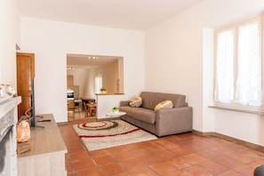Una sala de estar con sofá, televisión, chimenea y cocina al fondo.