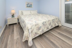 Une chambre à coucher avec un lit, une table de chevet, une lampe et une fenêtre.