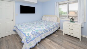 A bedroom with a bed, a dresser, a window with blinds, and a wall-mounted TV. - Walk to the Beach 2 BR Condo with a Shared Pool! Colony III 201 (Surfside Beach)