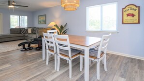 A dining area with a wooden table and white chairs, a sofa, and a ceiling fan. - Walk to the Beach 2 BR Condo with a Shared Pool! Colony III 201 (Surfside Beach)