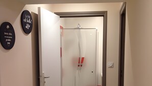 Ein Flur mit einer zur Kammer führenden Tür, einem an der Wand befestigten Schild und einem Lichtschalter.