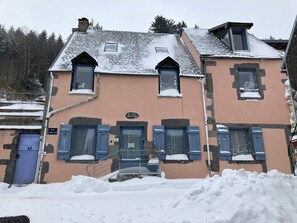A two-story building with a sloped roof, multiple windows, and a blue door. - Apartment 'La Maison Des Bains De César' with Mountain View and Wi-Fi (Mont-Dore)