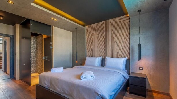 A modern hotel room with a large bed, bedside tables, and a unique textured wall design.