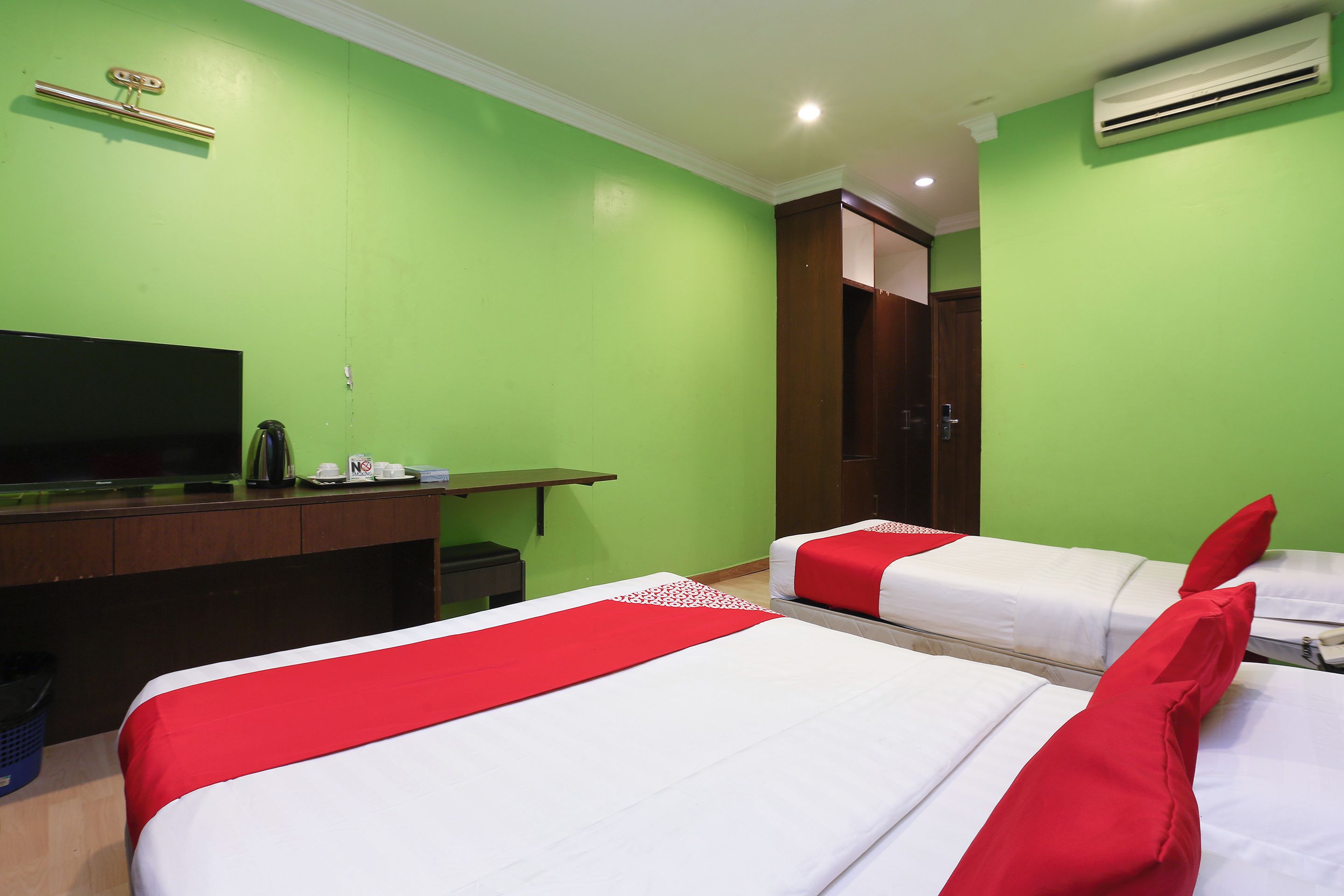 A hotel room with two beds, a desk with a television, and a wardrobe.
