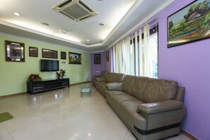 Una sala de estar con un sofá de cuero, un televisor de pantalla plana y una mesa de centro.