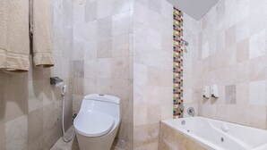 Ein Badezimmer mit Toilette, einer Badewanne und einer gefliesten Duschwand.