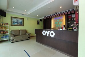 Una recepción con un letrero de neón que da la bienvenida a los huéspedes del hotel OYO.