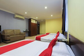 A hotel room with a sofa, two beds with red accents, a wardrobe, and an air conditioning unit. - OYO 90098 Goa Inn Hotel (Gua Musang)