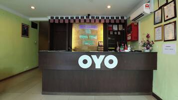 A reception desk with a neon sign reading 'Welcome to Goa Inn Hotel' and the name 'OYO' prominently displayed.