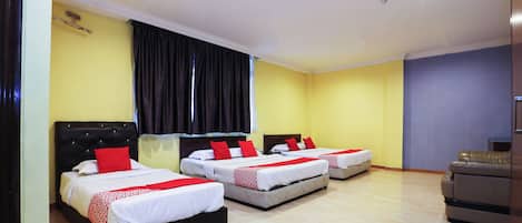 A hotel room with three beds, a desk, and a chair.