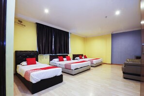 Habitación de hotel con tres camas, un escritorio y una silla.