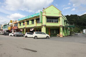Un hotel con fachada verde, múltiples ventanas y un cartel.