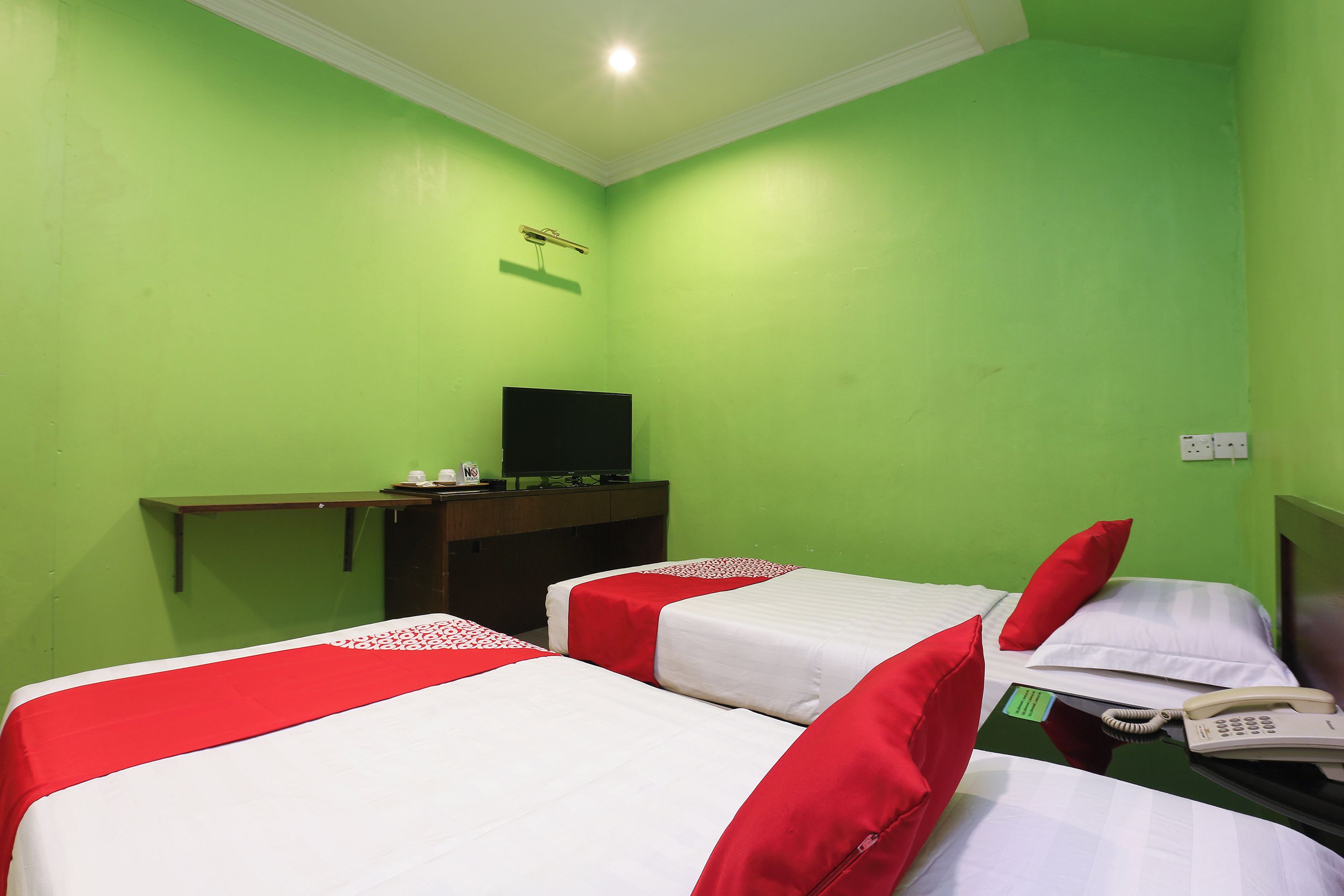 A hotel room with two beds, a desk with a television, and a telephone.