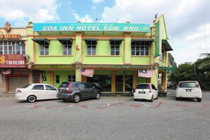 Un hotel con un letrero, varios coches aparcados y un cielo despejado.